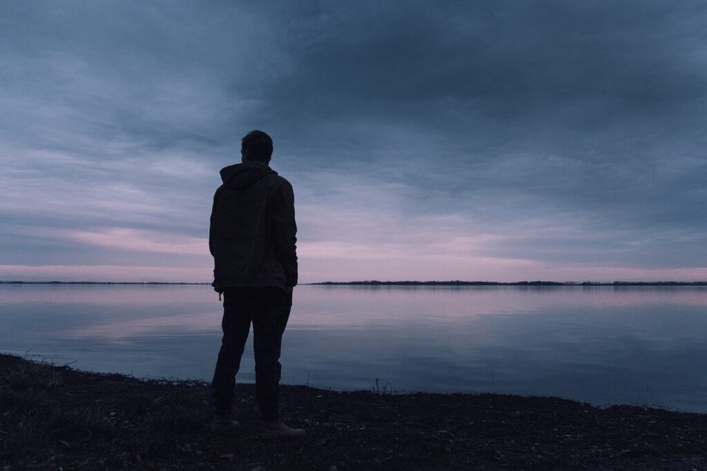 man staring off across a lake in a mysterious flash fiction