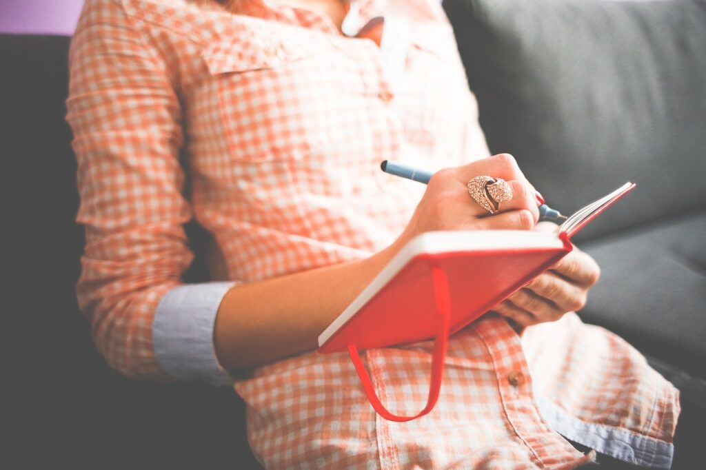 woman in pink jotting down creative ideas for writing